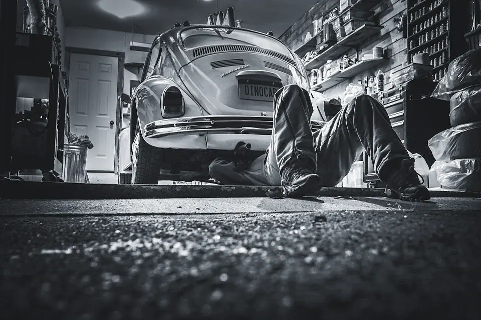 Profissional deitado sob um carro antigo na oficina